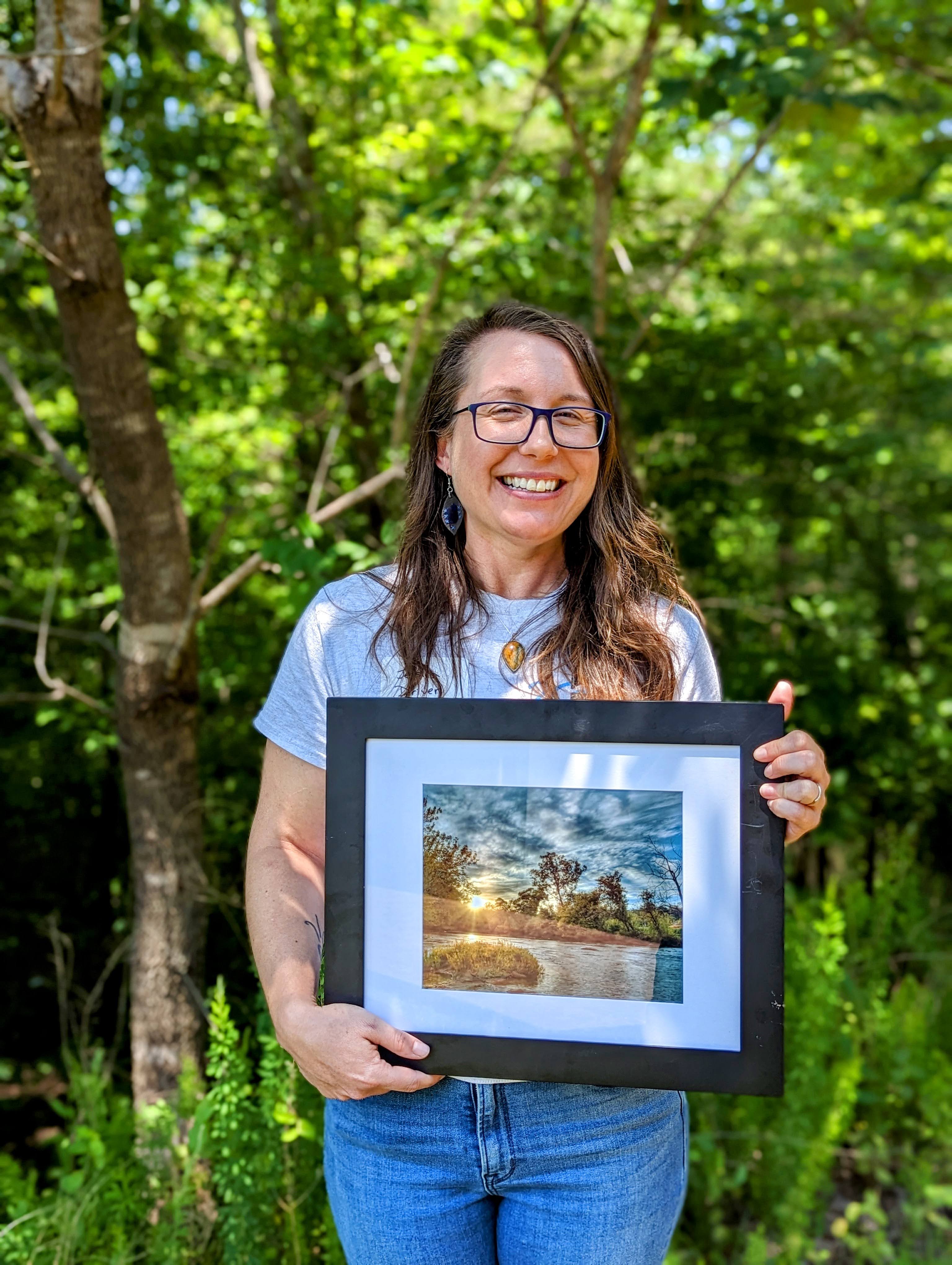 Jessica, an avid hiker, advocate, and naturalist, holding a beautiful print of the river given to her for the award